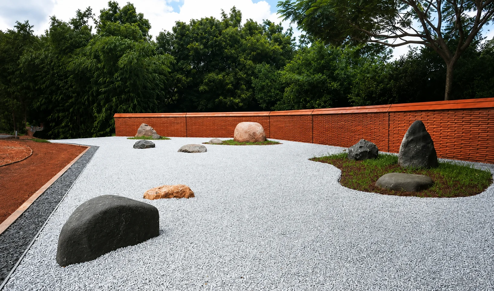 The Japanese Garden at Auroville Botanical Gardens in 2020, with stones set in white gravel beside a red brick wall