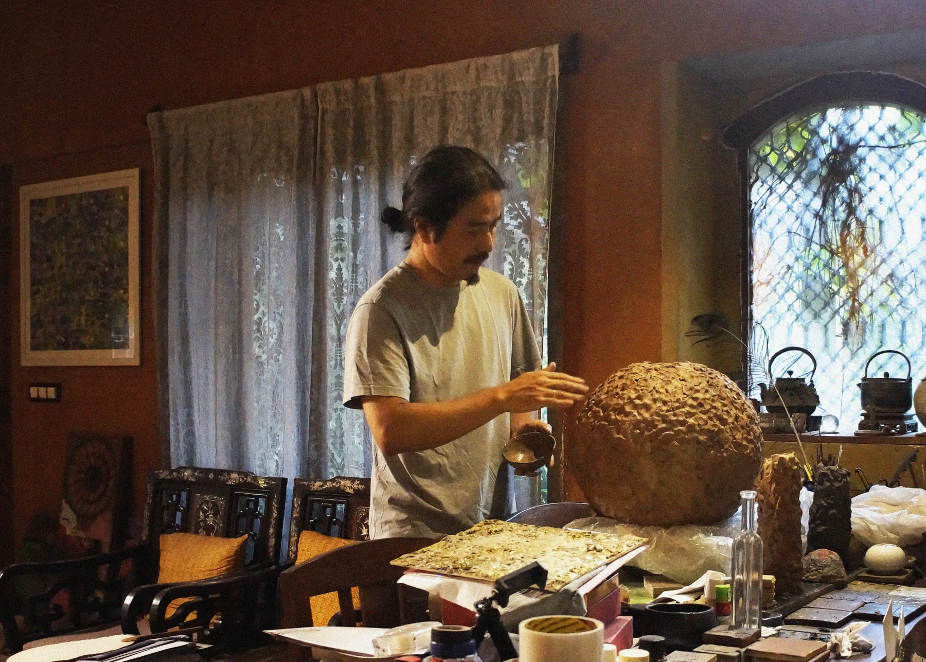 Jyoti Naoki Eri working by hand on a large textured sculpture in his studio