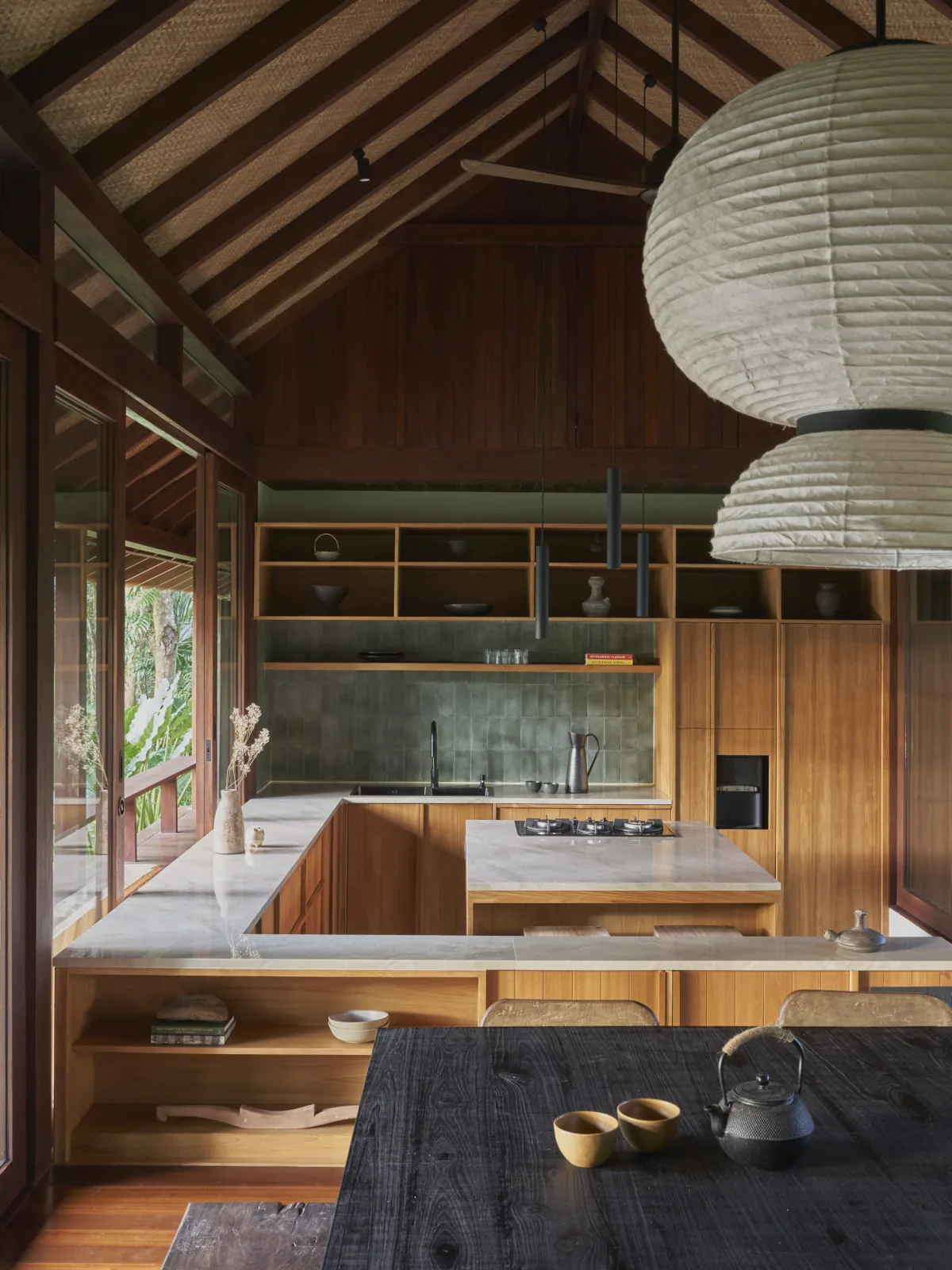 Kitchen and dining space beneath the woven karpet lontar ceiling at Rumah Haruku