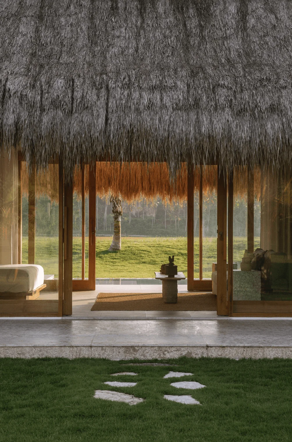 Garden villa entrance framed by thatch, timber and tropical planting