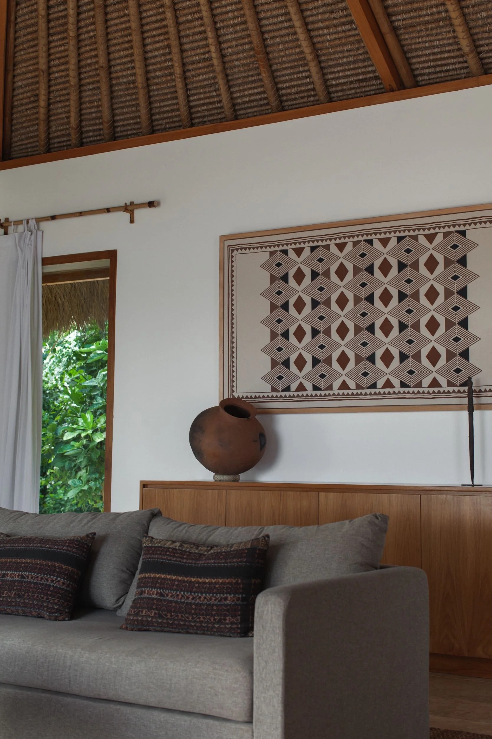 Living room with Sumbanese textiles, timber furniture and a thatched ceiling