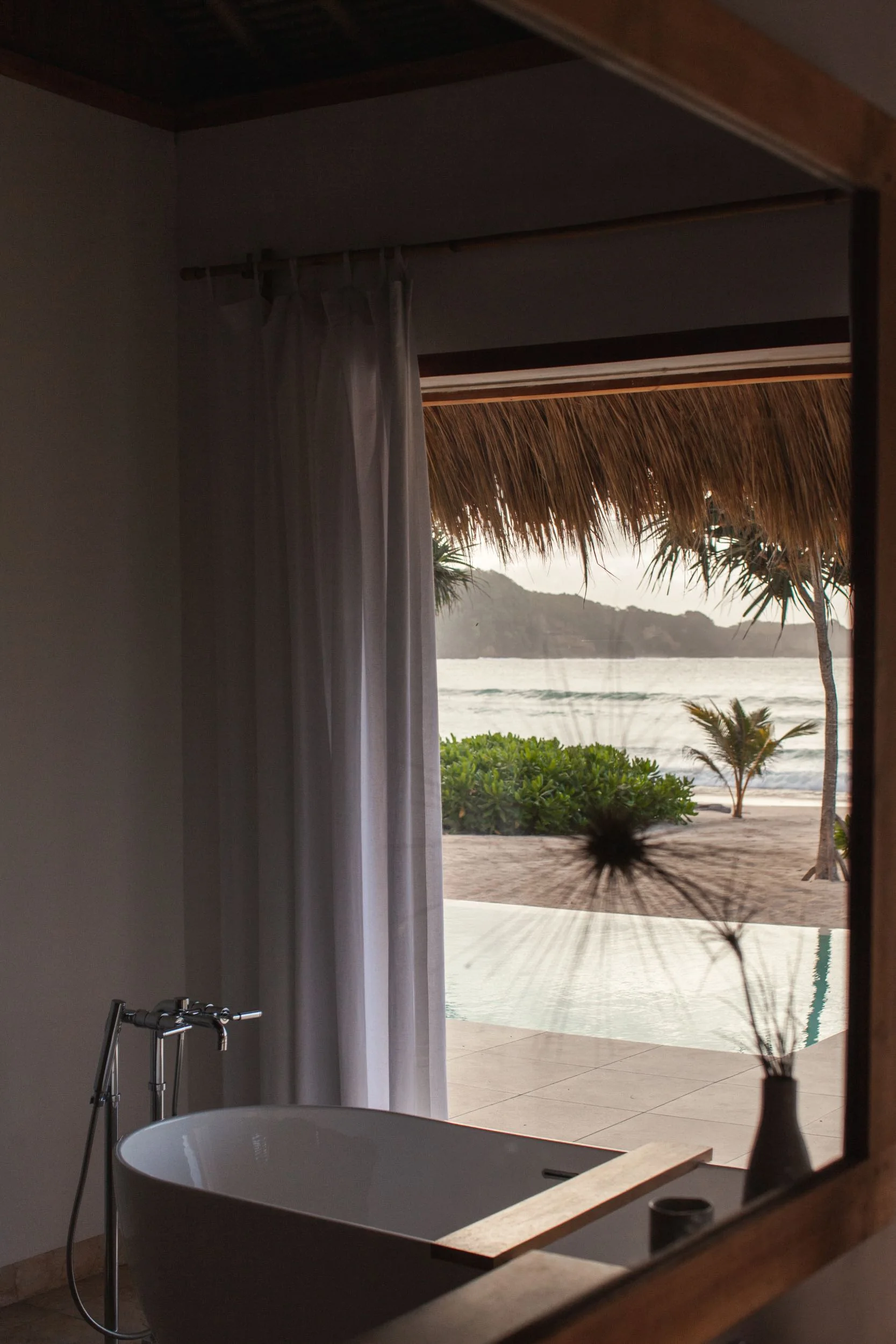 Freestanding bath oriented toward a private pool and the sea