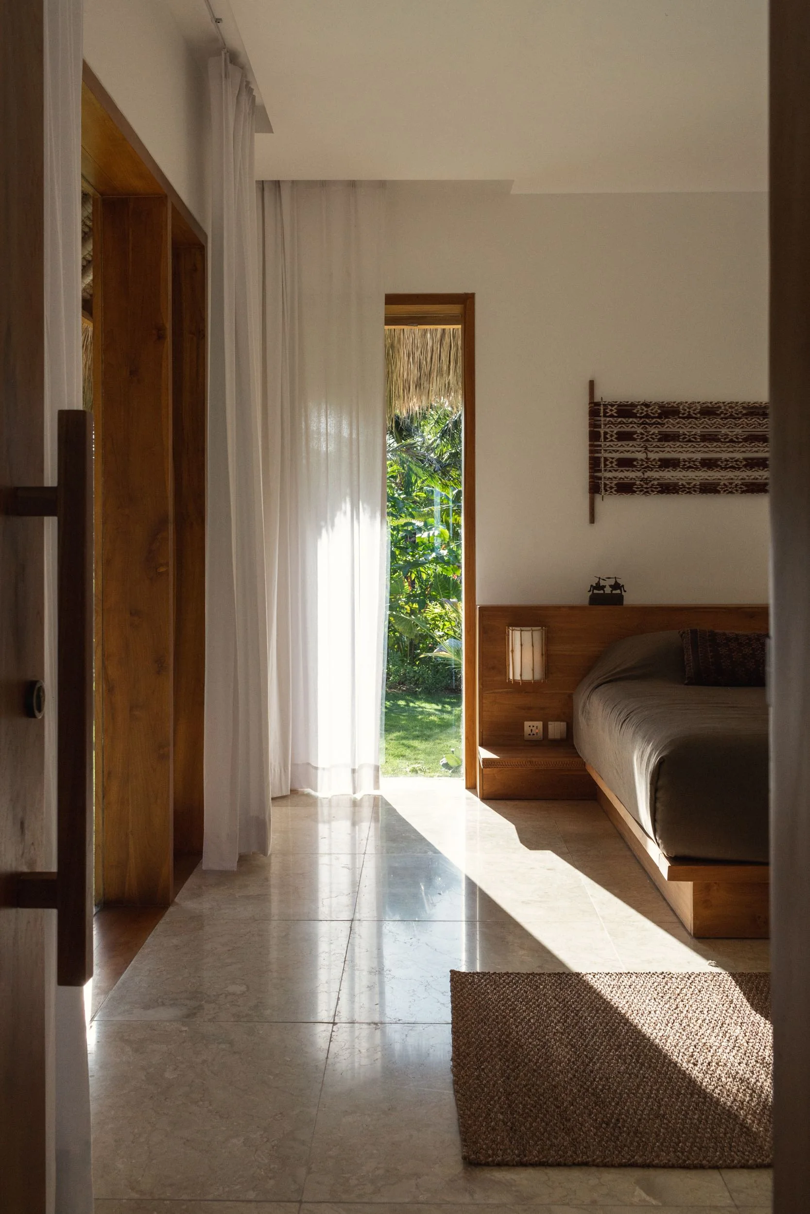 Sunlit bedroom with timber joinery, woven textiles and garden views