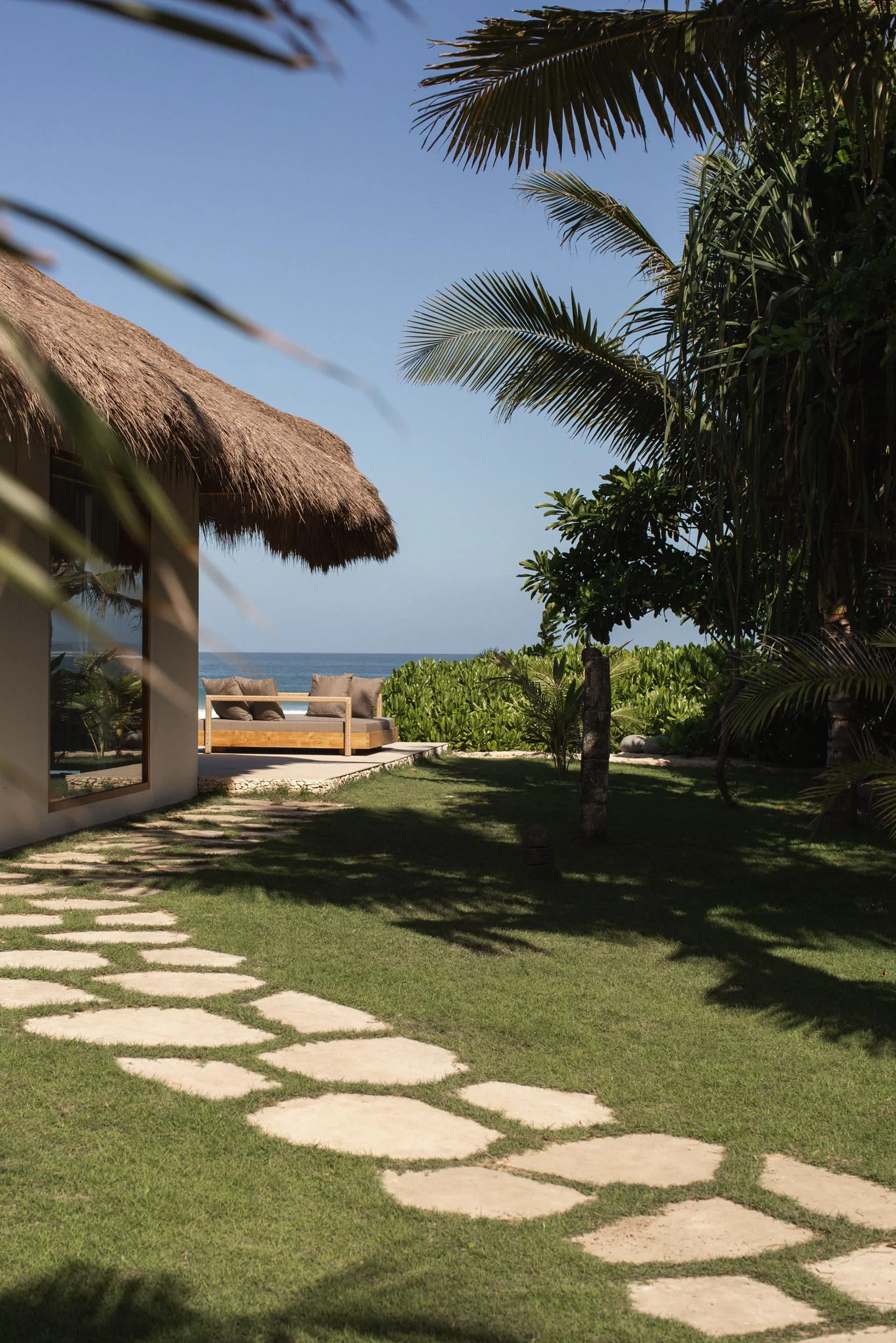 Shaded outdoor lounge framed by palms with the ocean beyond