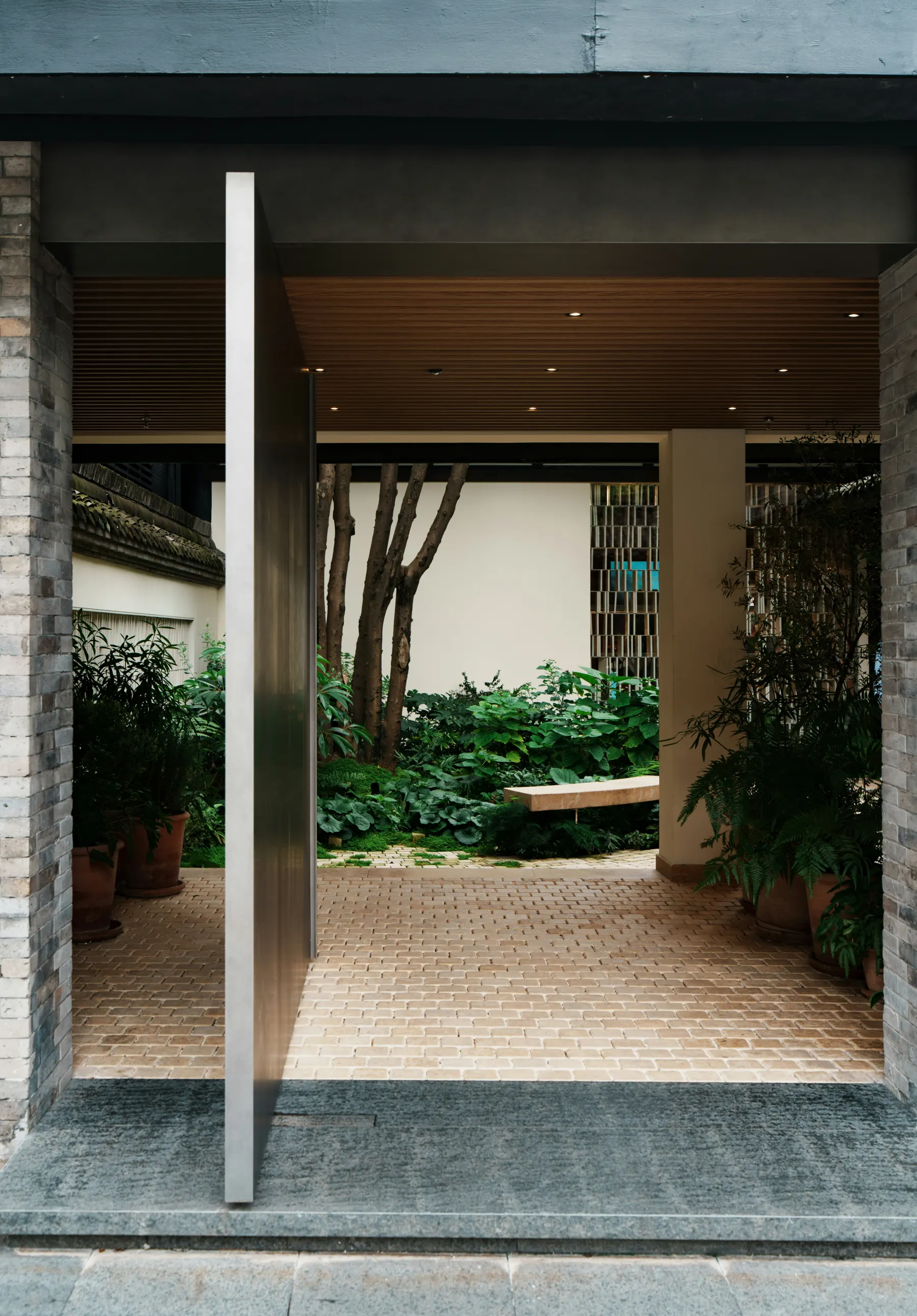 A covered tropical threshold opening into a planted garden