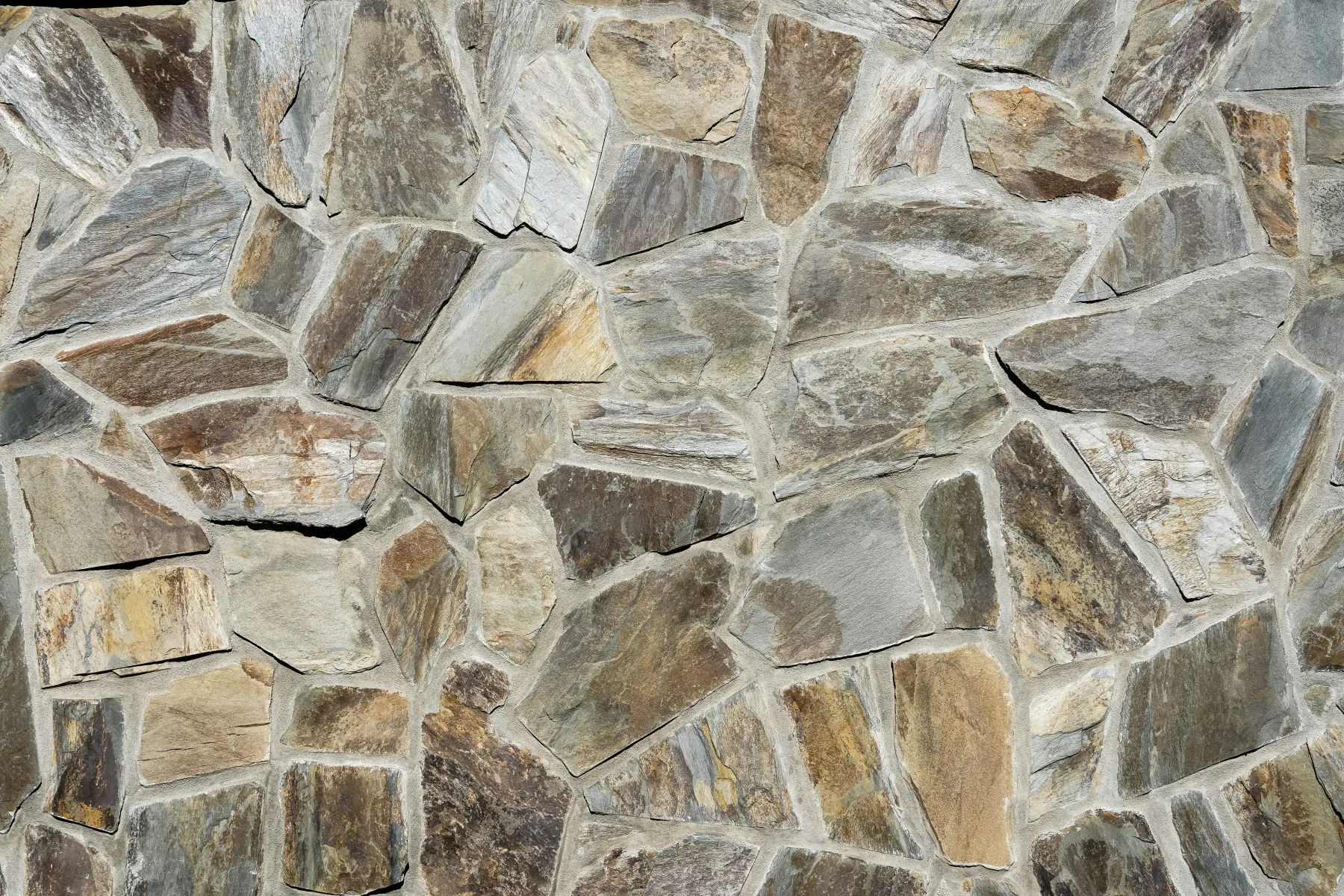 Natural stone wall texture with varied mineral colour, irregular shapes, and tactile surface depth