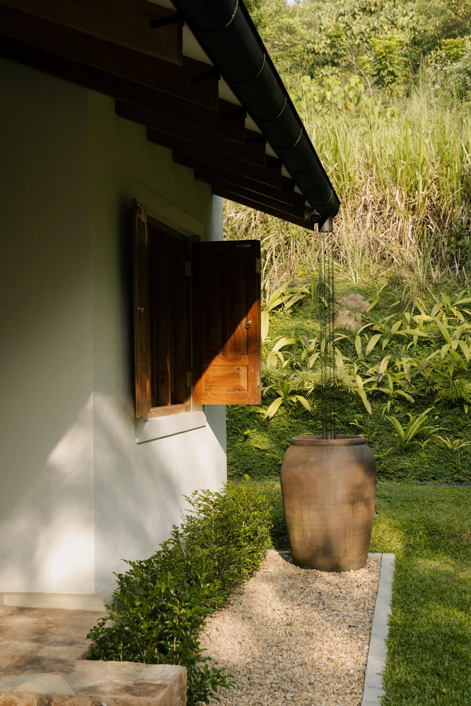 Teak-framed tropical window opening toward lush greenery and filtered daylight